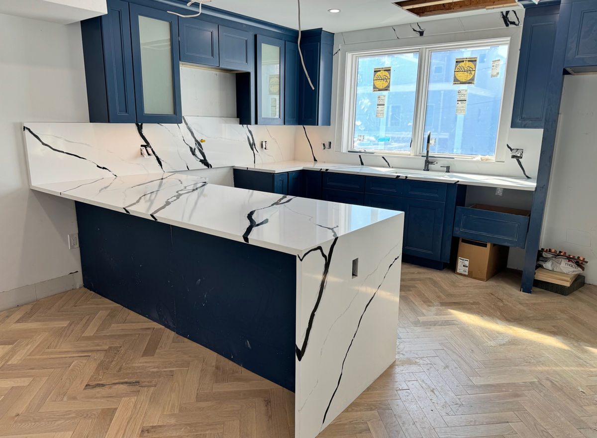 Calacatta-style quartz waterfall island installed in a navy-cabinet Philadelphia kitchen