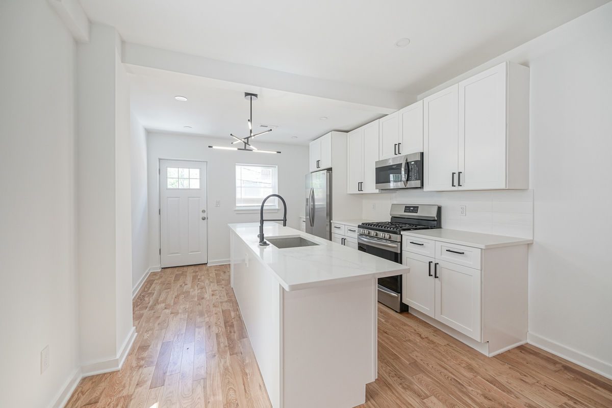 White quartz kitchen island with undermount sink in a finished Philadelphia rowhome kitchen