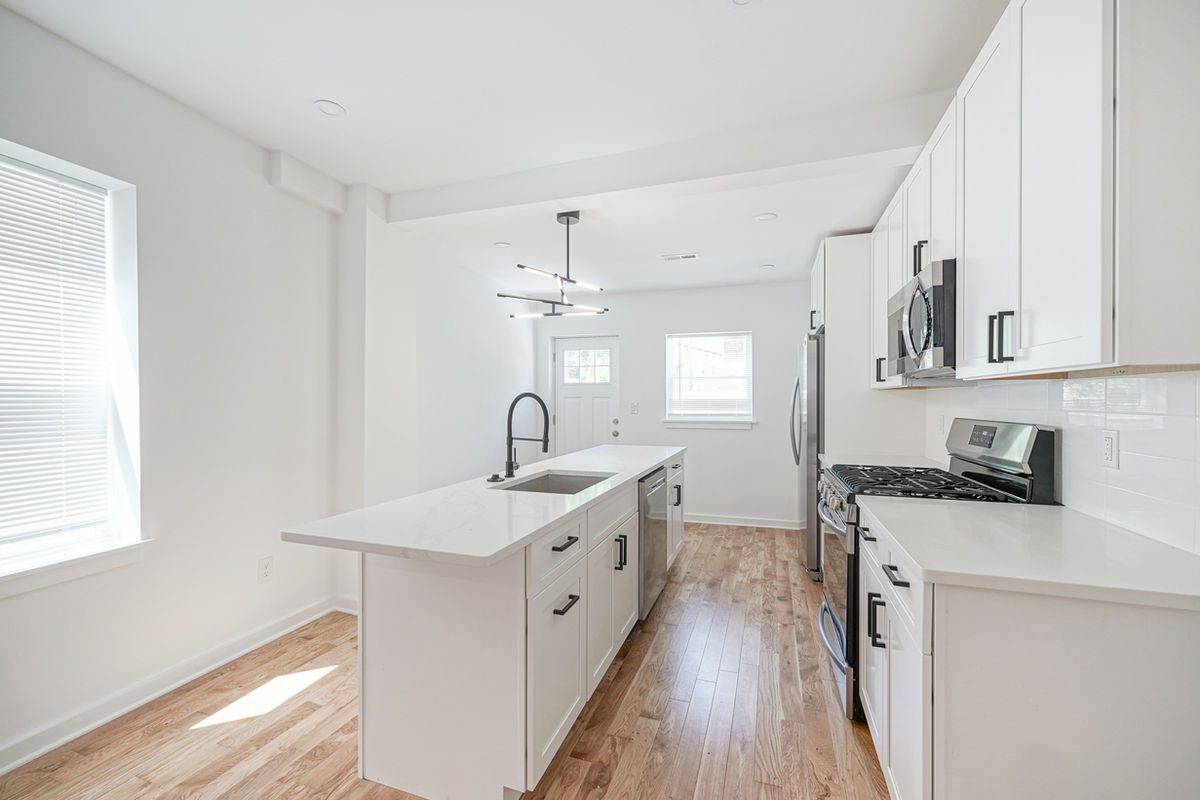 Long quartz countertop run along a galley-style rowhome kitchen