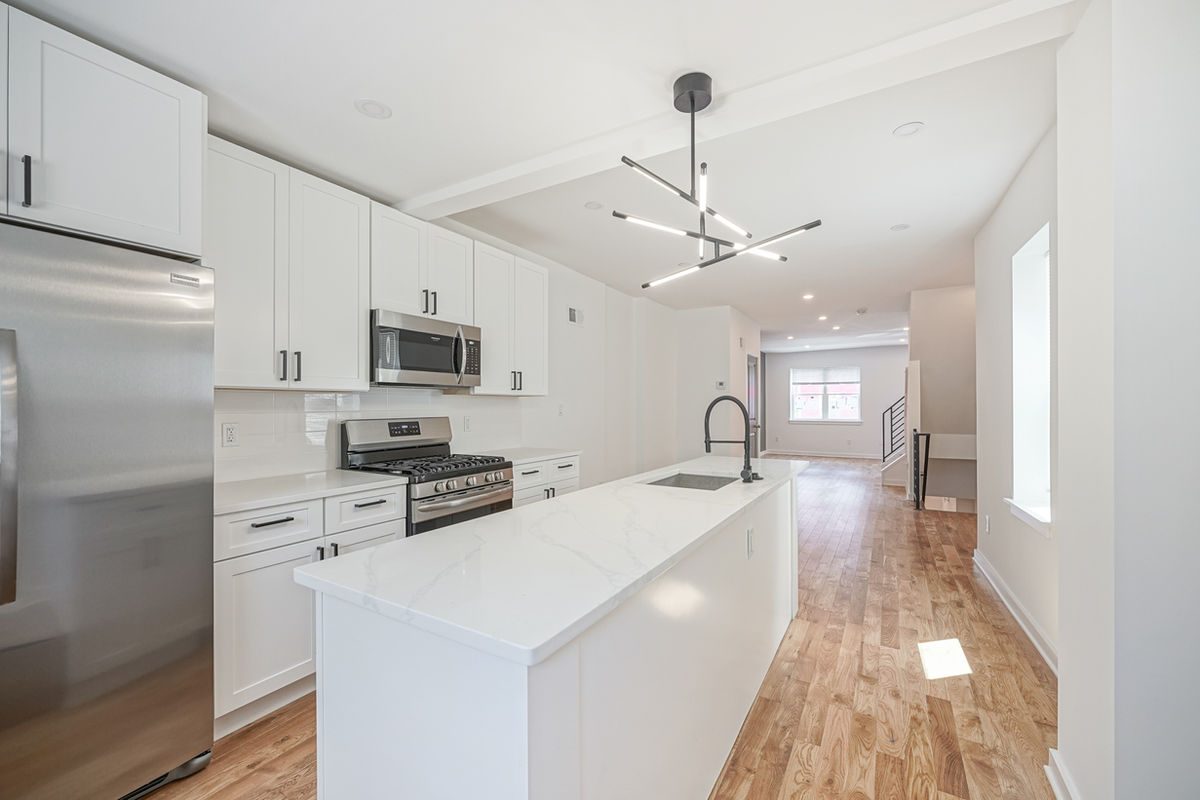 Quartz island and perimeter countertops in a bright finished kitchen