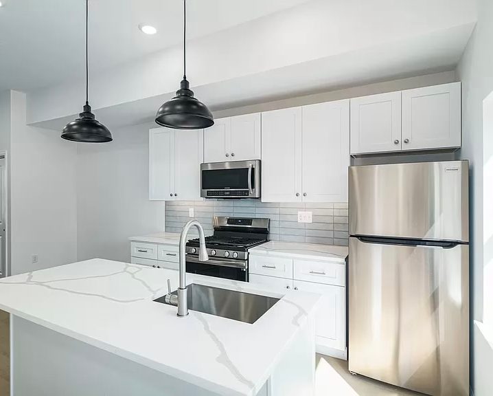 Quartz countertop and stainless appliances in a finished rowhome kitchen